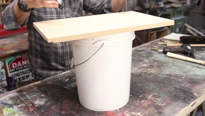 Prepare a Nail Catcher: Create a simple catcher using a bucket and a piece of wood with a slit cut into it. This prevents nails from flying across the room.