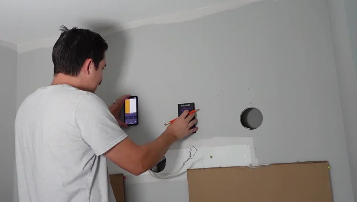 Use a stud finder to locate studs for wire routing. Draw a rectangle for the cutout and cut the drywall, drilling holes from the sides for easier access.