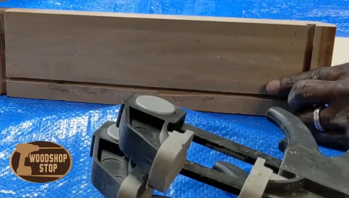 Glue a new piece of wood to the squared-off drawer face piece, ensuring a strong bond using clamps.