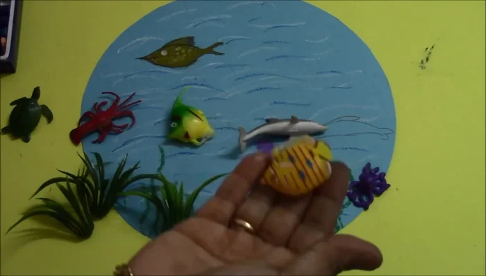 Add finishing touches: arrange and fix remaining fish, seashells, and stones using double-sided tape.