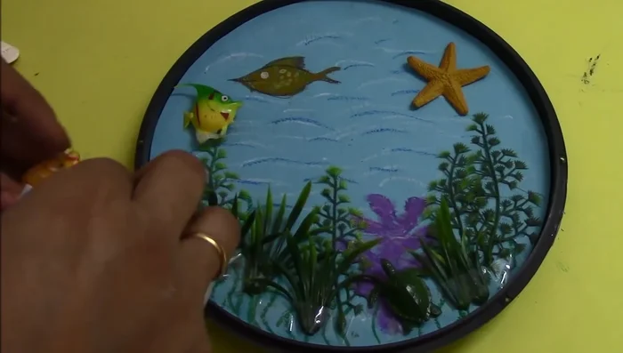 Add finishing touches: arrange and fix remaining fish, seashells, and stones using double-sided tape.