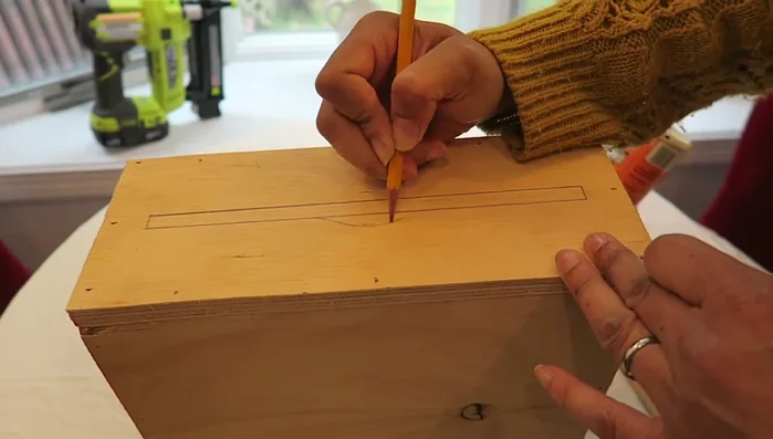 Create a template for the bottom opening, making the middle section wider for easy paper towel access. Cut the opening using a jigsaw.