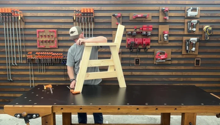 Attach the seat slats: Rest the first slat against the backrest supports and flush with the seat supports. Clamp, space using 2-inch screws, and fasten with 2 1/2-inch pocket hole screws. Repeat for remaining slats.