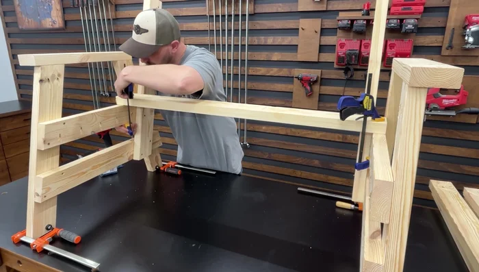 Attach the seat slats: Rest the first slat against the backrest supports and flush with the seat supports. Clamp, space using 2-inch screws, and fasten with 2 1/2-inch pocket hole screws. Repeat for remaining slats.