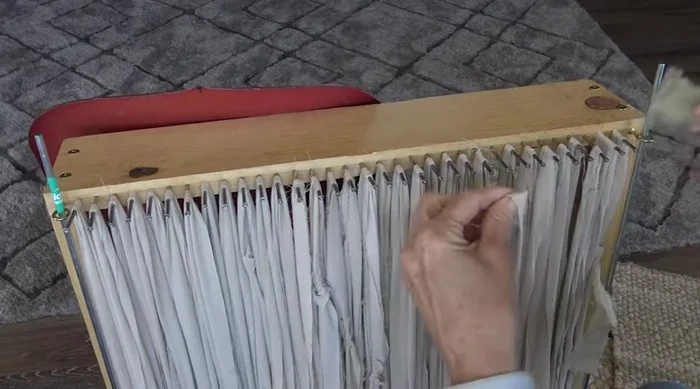 Start the first row: Begin weaving by going under and over two warp threads, securing your weaving around the steel rods to keep edges straight (504.16). Alternate colors and maintain tension.