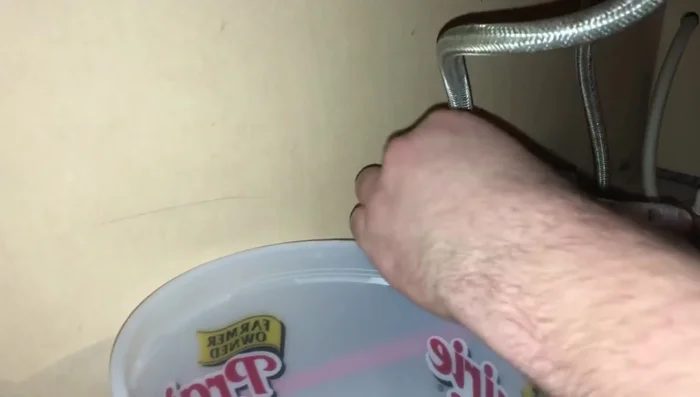 Turn on the cold water supply. The pressure will flush debris out of the hot water hose.