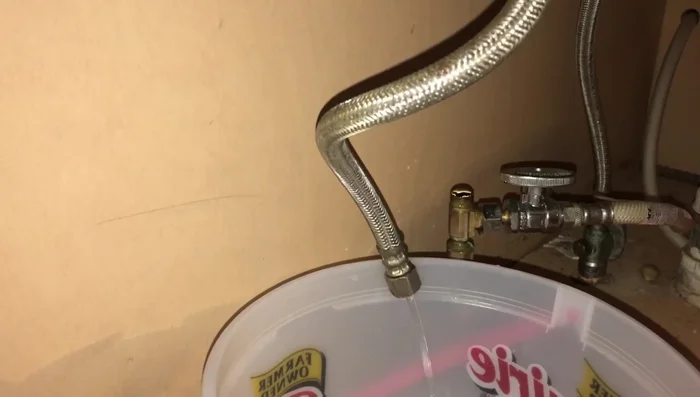 Turn on the cold water supply. The pressure will flush debris out of the hot water hose.