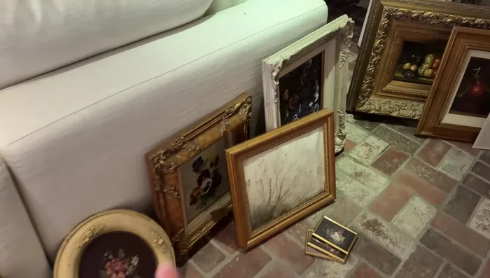 Begin hanging the art pieces, prioritizing a playful and intuitive approach. Don't overthink the arrangement.