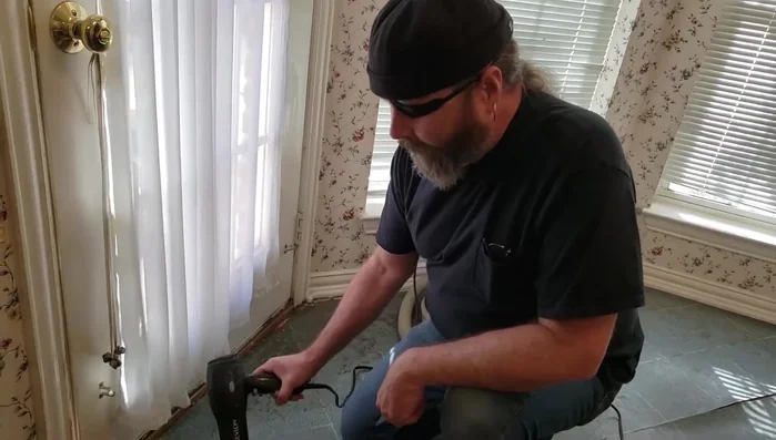 Clean out old adhesive and debris from underneath the separated linoleum seam using a scraper.