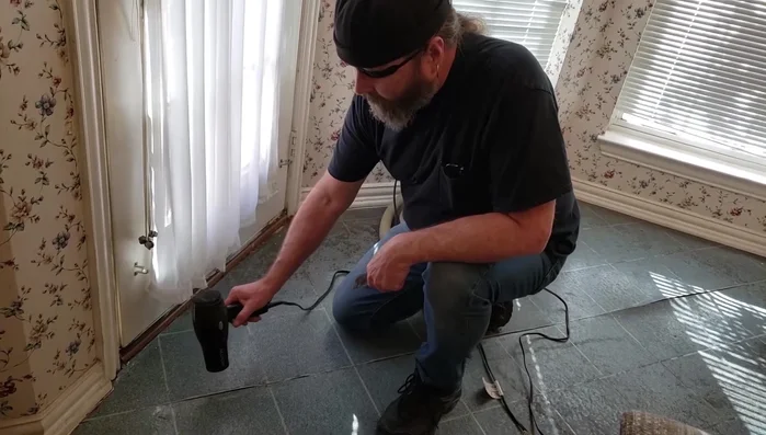 Clean out old adhesive and debris from underneath the separated linoleum seam using a scraper.
