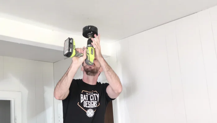 Cut 4 1/2-inch holes in the ceiling using a hole saw at your marked locations.