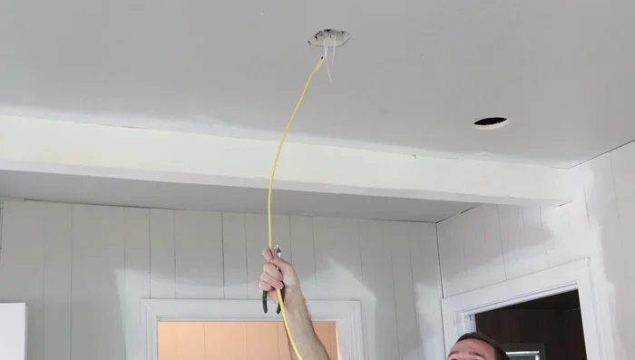 Run the Romex cable from the power source, snaking it between the light can locations.