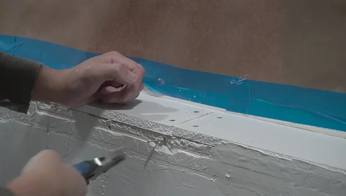 Apply joint compound to the back of the corner bead and install it, ensuring a tight fit and removing excess compound with a drywall knife.