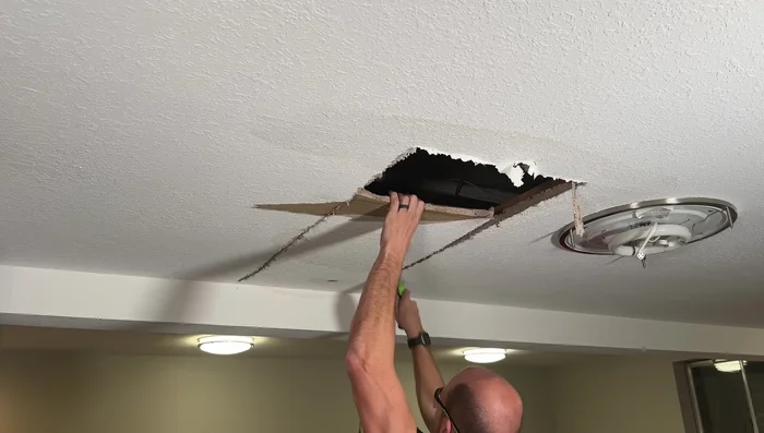 Cut larger holes to access the leak source.