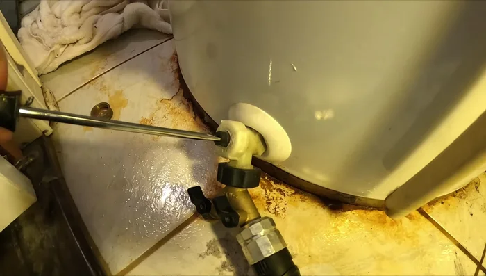 Drain the water from the tank. Use a splitter if needed for hose clearance. Open hot water faucets and disconnect the hot side line from the top of the water heater to allow air in.