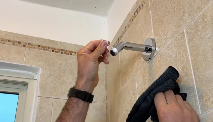 Clean the shower arm threads using a microfiber cloth to remove old thread tape and debris.