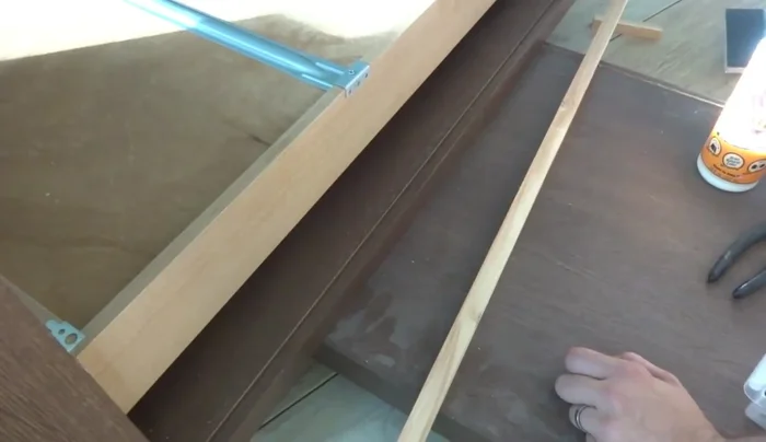 Create a back cover to conceal the drawer mechanism. Cut and attach a piece of wood to the back of the dresser, using small wood sticks for support.