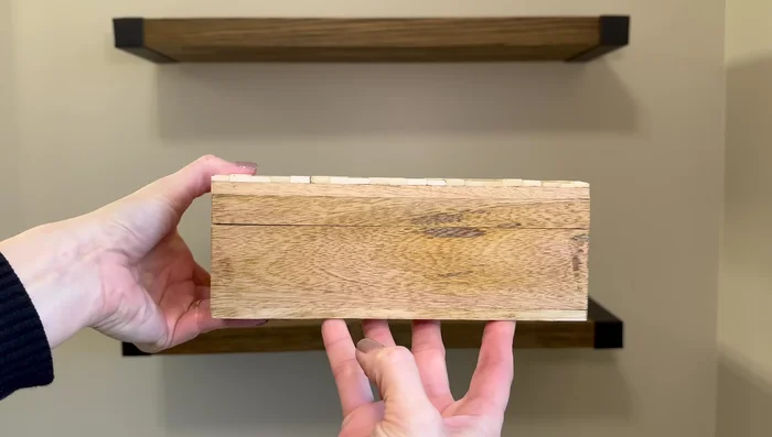 Decorate floating shelves with stackable boxes, small vases, greenery, a small canvas, and a wooden cube with a motivational saying.