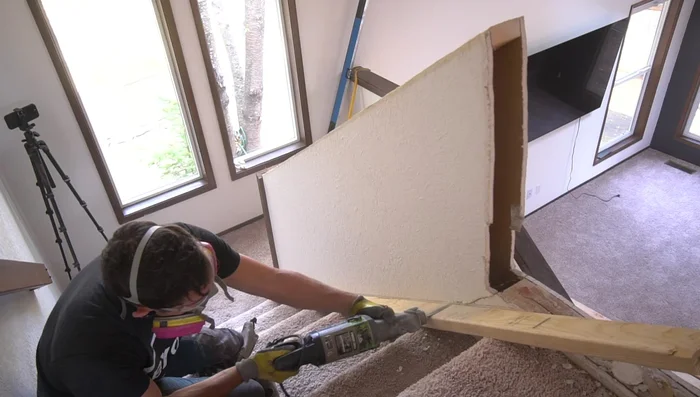 Using a 2x4 to trace the cut line ensures proper angle and ease of cutting with the reciprocating saw down the stairwell.